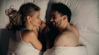 close-up-of-young-couple-lying-in-bed-facing-each-other-and-talking_nyitj6x_m__S0000